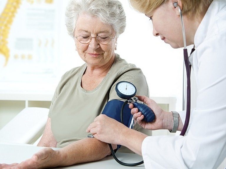 Orvos egy hölgy vérnyomását méri